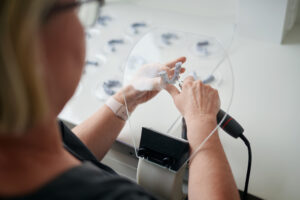 Mitarbeiterin bearbeitet kieferorthopädisches Modell – KFO Schlei Mitarbeiterin der Kieferorthopädie an der Schlei bearbeitet ein 3D-gedrucktes Zahnmodell im praxiseigenen Labor