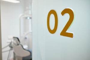 Behandlungszimmer 02 – Kieferorthopädie an der Schlei Eingang zum Behandlungsraum 02 der Kieferorthopädie an der Schlei mit Glastür und Kennzeichnung