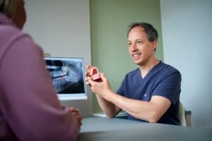 Patientenberatung beim Kieferorthopäden Helge Müller-Stephan Kieferorthopäde Helge Müller-Stephan erklärt einer Patientin anhand eines Kiefermodells und Röntgenbild die Behandlung