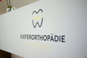 Logo Kieferorthopädie an der Schlei am Empfangstresen Praxislogo „Kieferorthopädie an der Schlei" am Empfangstresen der Praxis in Schleswig