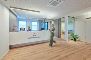 Empfangsbereich der Kieferorthopädie an der Schlei Freundlicher Empfangsbereich der Kieferorthopädie an der Schlei mit Empfangstresen und Praxislogo